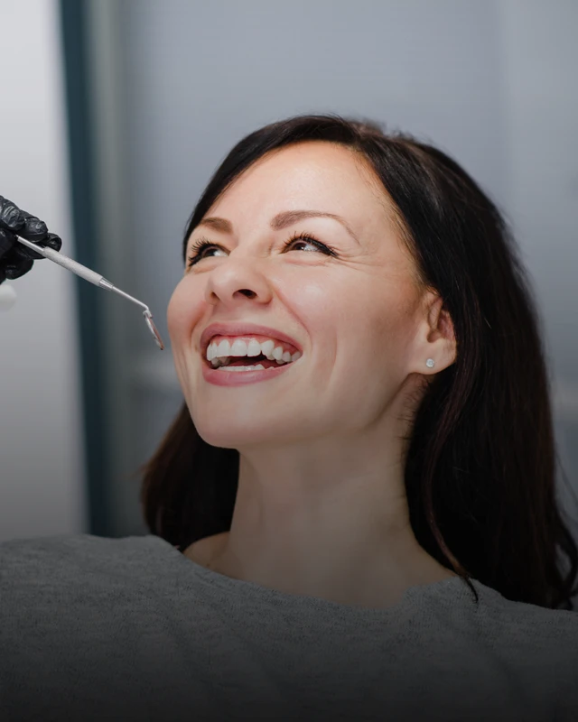A patient smiling while opening her mouth during a dental examination